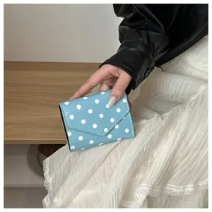 Primo piano dettagliato di un piccolo portafoglio azzurro a pois bianchi e design liscio.