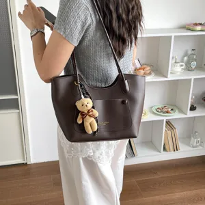 Vue détaillée d'un sac cabas marron rétro élégant avec un joli charme d'ours mignon.