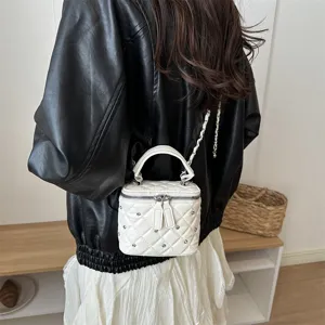 Quilted white mini top-handle crossbody bag detail shot, stylish chain strap and chic design.