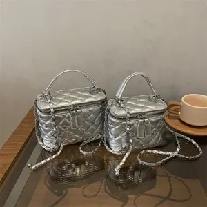 Detail view of silver quilted chain crossbody bag with structured vanity box design and handle.