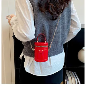 Petit sac cylindrique rouge en cuir verni avec bandouliere chaine pour femme.