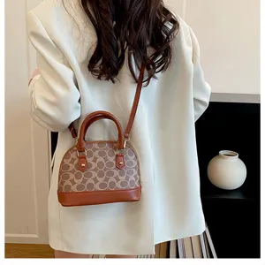 Detail view of stylish women shell crossbody bag with monogram print and brown leather trim.