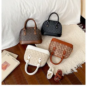 Detailed view of women's stylish dome handbag with classic monogram pattern and shoulder strap.