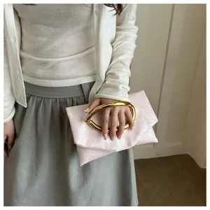 Detail shot of a stylish pink clutch bag featuring a statement gold oval handle for daily use.