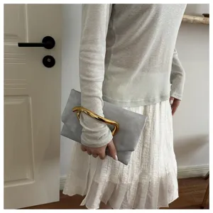 Elegant grey leather clutch bag with a striking gold sculptural handle for women evening party.
