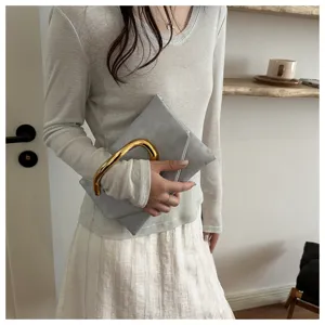 Close-up detail of stylish grey clutch bag with unique gold curved handle, fashion accessory.