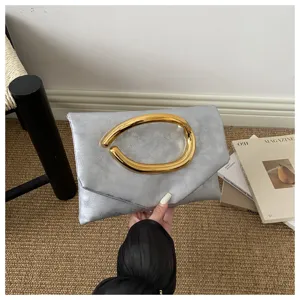Silver clutch bag with unique golden sculptural handle, stylish evening bag for women fashion.
