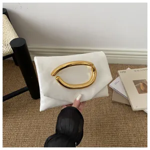 White faux leather clutch bag with a striking gold-tone curved handle, chic evening style.