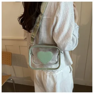 Vue détaillée du sac bandoulière transparent avec cœur vert et large sangle au style casual.