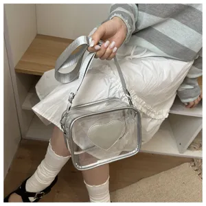 Sac bandoulière transparent en PVC, détail avec large sangle et motif de cœur à l'avant.