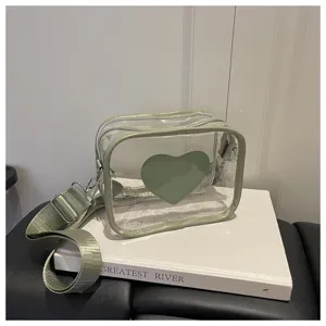 Sac bandoulière transparent en PVC avec cœur vert et large sangle, style décontracté.