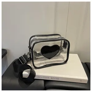 Sac bandoulière transparent avec bordure noire et motif cœur ainsi qu'une sangle réglable.