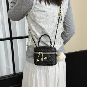 Vue détaillée du sac bandoulière matelassé noir avec accessoires dorés et adorables charms.