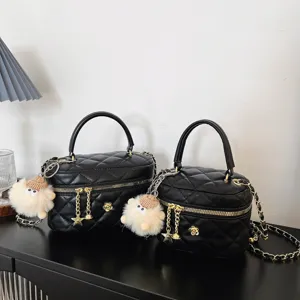 Détail du sac à main matelassé noir avec chaîne dorée et joli pendentif en peluche pour femme.
