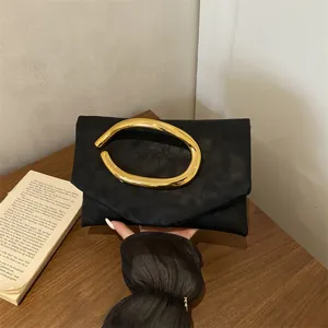 Chic black evening clutch bag with unique gold abstract handle, elegant minimalist fashion purse.