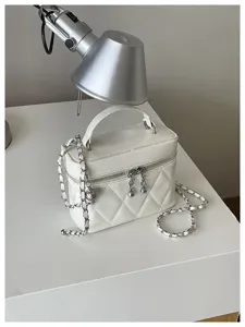 Gros plan du sac vanity matelassé blanc, détails élégants de bandoulière chaîne et texture.