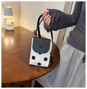 Detail view of the stylish black and white polka dot shoulder bag and phone bag display.