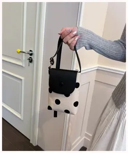Close-up detail of the chic black and white polka dot crossbody phone bag with leather flap.
