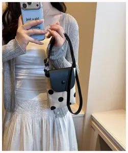 Detail view of a chic black and white polka dot mini crossbody shoulder phone bag.