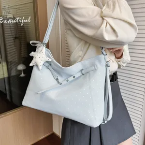 Detailed view of light blue polka dot shoulder bag with cute star pendant and stylish straps.
