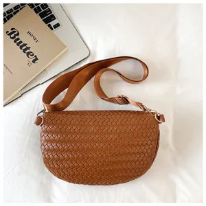 Sac bandoulière en cuir tressé marron, vue détaillée montrant la texture et la sangle.
