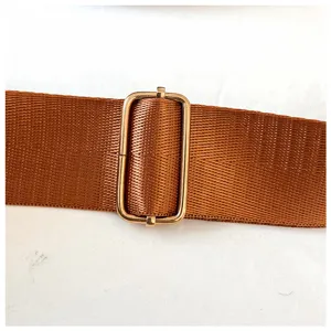Gros plan sur la sangle de sac marron réglable avec boucle coulissante en métal doré pour sac.