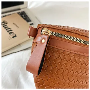 Sac bandoulière en cuir tressé marron, vue de détail élégante avec fermeture éclair métallique.