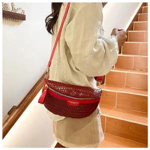 Vue détaillée du sac-selle en cuir tressé rouge porté par le modèle, accessoire de mode.