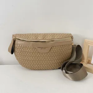 Vue détaillée du sac de selle en cuir tressé beige avec sangle large et fermeture éclair dorée.