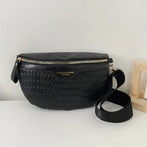 Sac bandoulière noir en cuir tressé avec fermeture éclair dorée et large sangle.