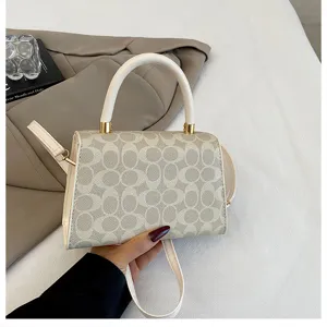 Primer plano del bolso de mano monograma para mujer con asa elegante y detalles dorados.