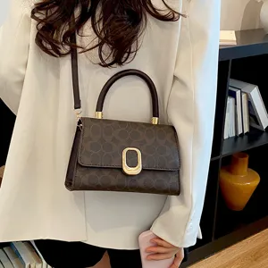 Primer plano de los detalles del bolso cruzado monograma marrón con elegante herraje dorado.