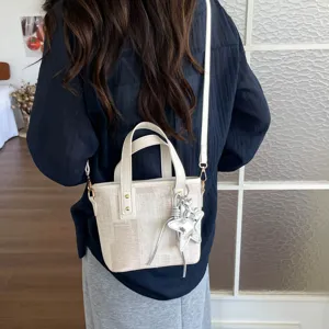 Detail view of minimalist chic canvas bucket bag with star charm and shoulder strap.