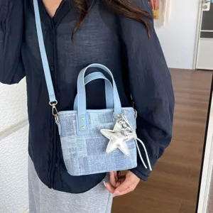 Detailed close-up of a stylish light blue denim bucket bag featuring a cute silver star charm.