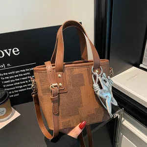Close-up detail of stylish brown bucket shoulder bag with chic star pendant and dual handles.