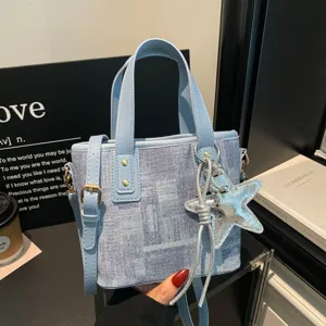 Blue denim bucket handbag with top handles, crossbody strap and shiny star charm.