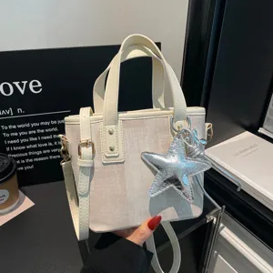 Detail shot of a chic beige canvas bucket bag with a stylish silver star pendant and handle.