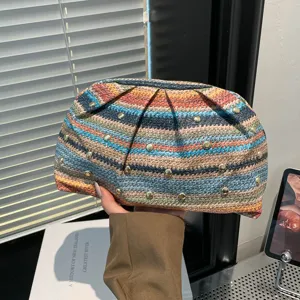 Vue détaillée d'une pochette en paille tressée colorée avec des clous décoratifs.