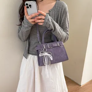 Close-up of the purple crossbody handbag highlighting belt buckle and lace pearl charm.