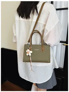 Grüne Canvas Handtasche mit braunem Leder, Tragegriff und verstellbarem Schultergurt.