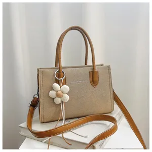 Detailansicht der khaki leinenen Umhängetasche mit einem charmanten weißen Blumenanhänger.