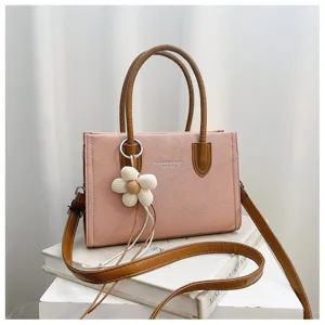 Detailaufnahme der rosafarbenen Canvas Handtasche mit braunen Griffen und Blumendekor.