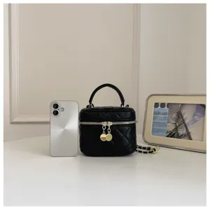 Black quilted vanity bag with top handle, chain strap, and double zipper closure.
