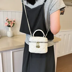 White quilted crossbody vanity bag detail, chic chain strap and elegant top handle.