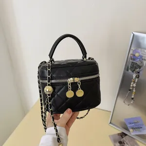 Black quilted chain vanity bag detail shot, featuring luxury style, elegant gold hardware and top handle.