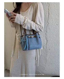 Retro denim bucket bag with brown leather trim, metal turn-lock and chic charm details.