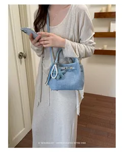 Denim bucket bag detail showing turn-lock closure and cute pearl star charm for women.