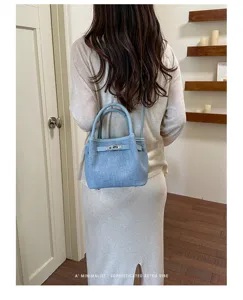 Detailed view of the retro denim bucket shoulder bag featuring metal lock and handles.