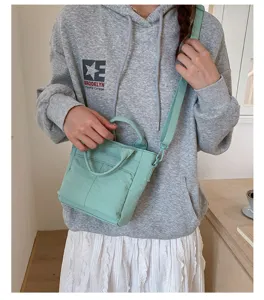 Detailopname van een mintgroene canvas crossbody tas, casual handtas gedragen door model.