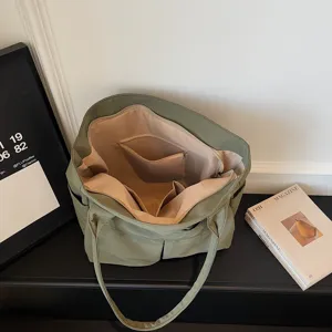 Vista dettagliata della grande borsa tote verde con scomparti multipli e tasche interne.